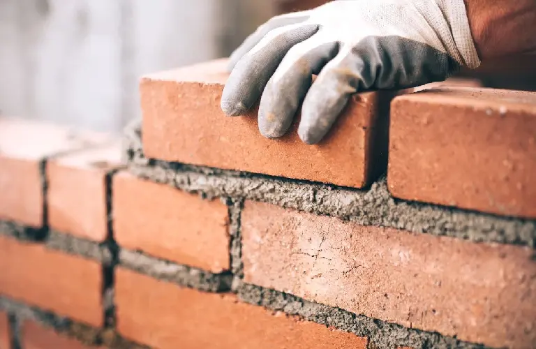 Close up of industrial bricklayer installing bricks on construction site